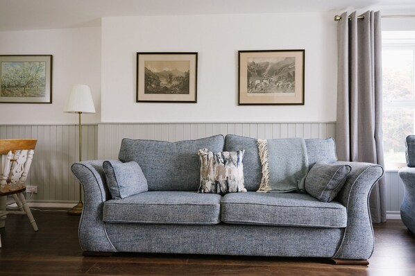 A grey woven sofa with a herringbone pattern, a white lamp, and two framed landscape paintings on the wall. - Luxury Farmhouse with Lough Eske Lake View | Nr Harveys Point/Lough Eske Castle (Barnesmore)
