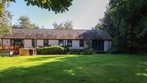 A single-story building with a sloped roof, surrounded by a well-maintained lawn and mature trees. - Woodcutters (Launceston)