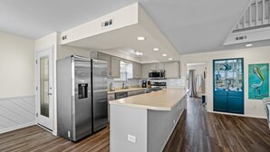 Une cuisine moderne dotée d’appareils électroménagers en acier inoxydable, d’un grand îlot central et d’un mur d’accent bleu.