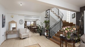 Un vaste espace de vie comprenant un escalier, un coin repas et une vue sur l’extérieur.