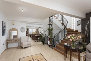 A spacious living area with a staircase, a dining area, and a view to the outside. - Villa Beach Heaven - Seven Bedroom Villa, Sleeps 16 (Pomos)