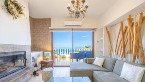 Un salon moderne doté d’une cheminée, d’un canapé, d’une table basse et d’un balcon offrant une vue sur la mer.