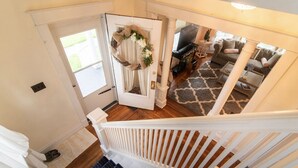 Una escalera conduce a una sala de estar con chimenea, televisor y sofá.