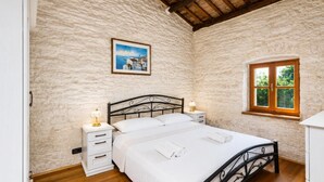 Ein Schlafzimmer mit einem Bett, Nachttischen, einem Fenster und einem Bild an der Wand.