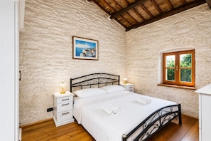 Ein Schlafzimmer mit einem Bett, Nachttischen, einem Fenster und einem Bild an der Wand.