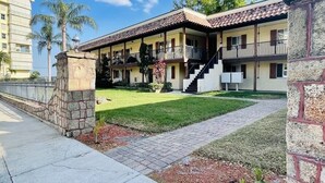 A two-story building with a balcony on the upper floor, a stone pillar, and a paved walkway. - Newly Renovated Water Front in Historic Cocoa Village with Pool! (Cocoa)