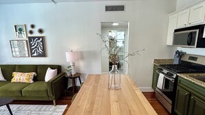 A modern kitchen with a wooden island, white cabinets, and a green accent wall. - Newly Renovated Water Front in Historic Cocoa Village with Pool! (Cocoa)