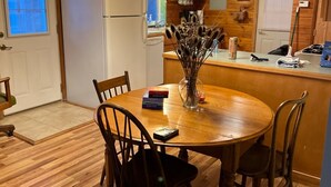 A cozy kitchen with wooden cabinets, a white refrigerator, a dining table with chairs, and a chandelier.