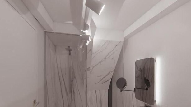 A modern bathroom with a marble wall, a built-in shower, and a vanity with a mirror.