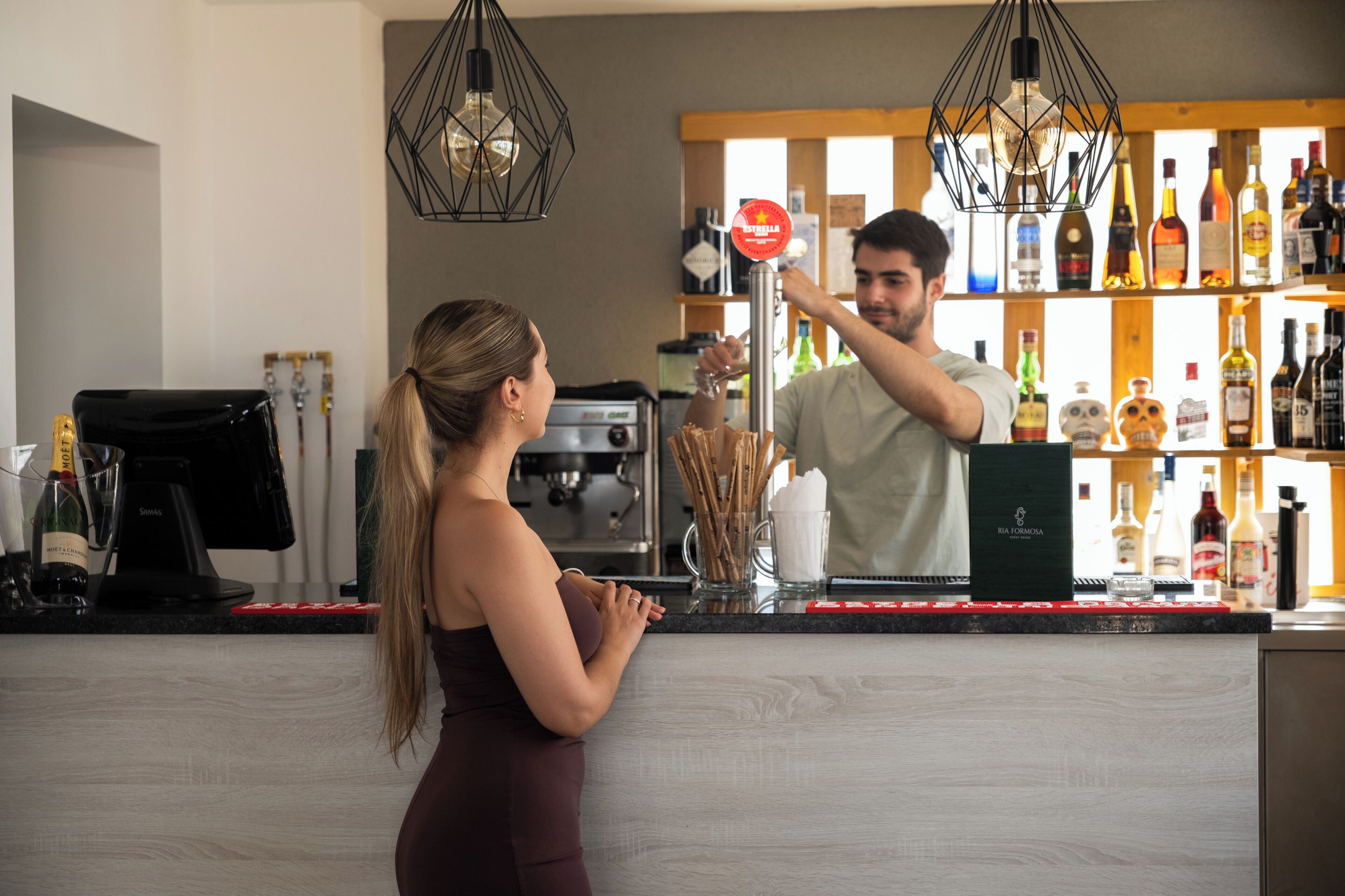 Zona de bar con mostrador, máquina de café y varias botellas de alcohol.