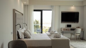 Ein modernes Hotelzimmer mit einem großen Bett, einem Schreibtisch, einem Sessel, einem Fernseher und einem Balkon mit Blick.