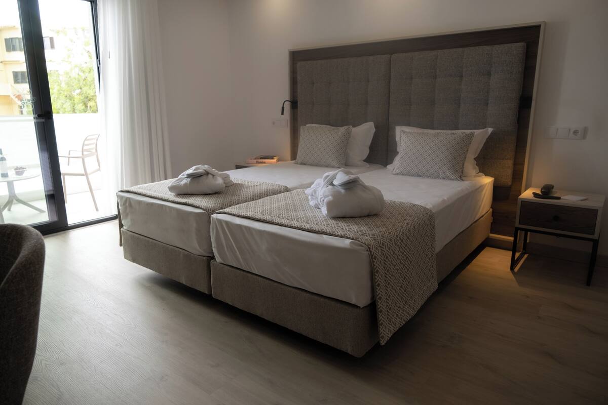 A double bed with a headboard, two bedside tables, a small table, and a chair.