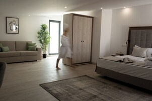 Un dormitorio moderno con una cama grande, un armario, un sofá y una planta en maceta.