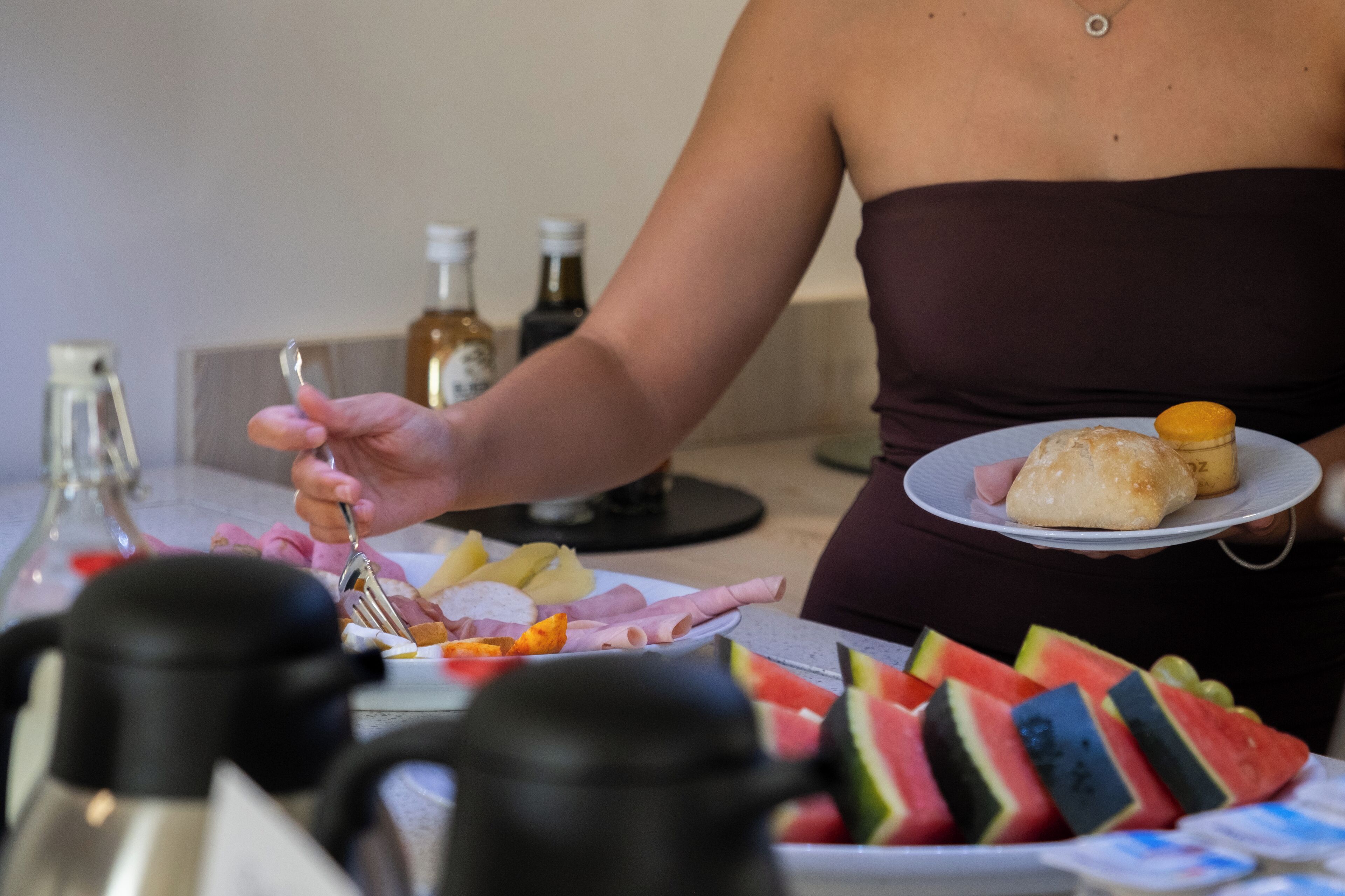 Una persona sirve comida de un plato con pan y una naranja pequeña.