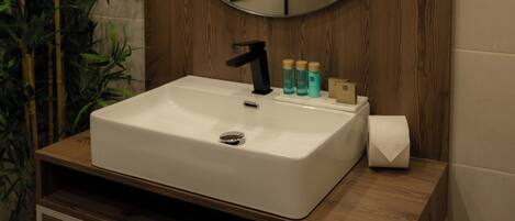 Une salle de bain avec un meuble-lavabo en bois, un miroir rond, un évier et une plante en pot.