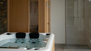 Ein modernes Badezimmer mit einer gläsernen Duschkabine, einem Holzschrank und einer weißen Badewanne mit mehreren Düsen.