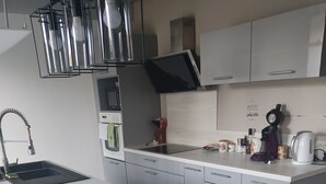 Una cucina moderna con isola centrale, elettrodomestici in acciaio inossidabile e televisore a schermo piatto.