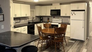 Une cuisine moderne avec des meubles blancs, un plan de travail noir et un îlot central doté de tabourets.