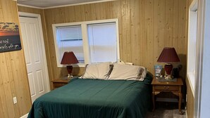 Une chambre à coucher avec un lit, deux tables de chevet, une fenêtre et une porte.