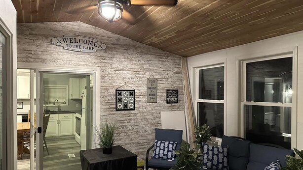 Un salon chaleureux avec un plafond en bois, un panneau d’accueil, une cheminée et un coin salon comprenant un canapé et des fauteuils.