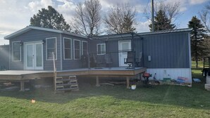 Une maison à deux étages avec une terrasse, un garage et un petit espace extérieur équipé d’un barbecue.
