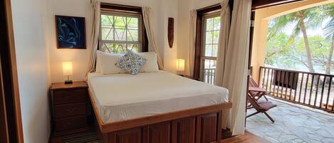 A bedroom with a wooden bed, a ceiling fan, and a view of the outdoors through a window.