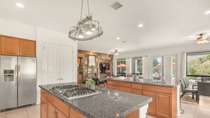A modern kitchen with a central island, stainless steel appliances, and a dining area with a view. - Pool*Spa*Games*Golf*Polo*Festivals*4BR+2BR Casita (Indio)