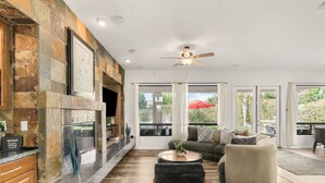 A modern kitchen with a stone backsplash, a fireplace, and a dining area with a red umbrella. - Pool*Spa*Games*Golf*Polo*Festivals*4BR+2BR Casita (Indio)