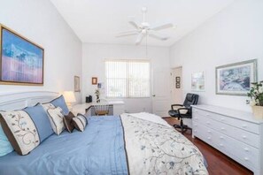 A bedroom with a bed, a desk, a chair, a dresser, and a ceiling fan. - Unique comfortable Golf course Home w Private Pool (Davenport)