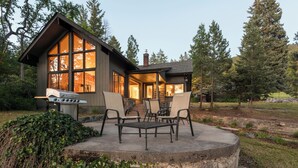 Een modern huis met een terras voorzien van tuinmeubilair en een barbecue.