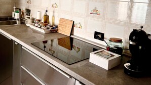 A modern kitchen with stainless steel appliances, a tiled backsplash, and a built-in oven. - La Casa di Cri (Asti)