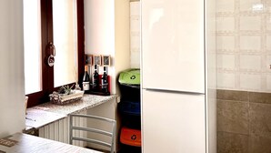 A kitchen with a refrigerator, a window, and a trash bin. - La Casa di Cri (Asti)