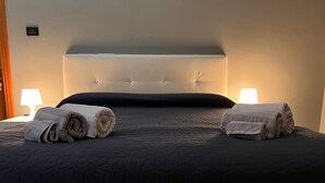 A neatly made bed with a dark quilted bedspread and two rolled towels on either side. - La Casa di Cri (Asti)