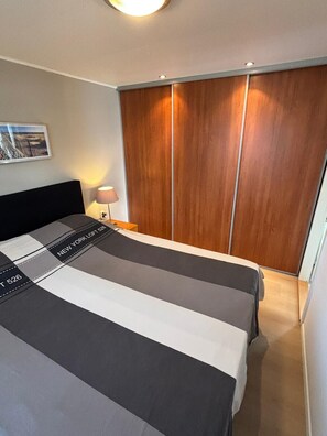 Ein Hotelzimmer mit einem Bett, einem Nachttisch, einer Lampe und einem Kleiderschrank.