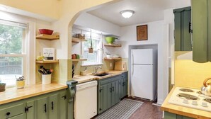 Una cocina con gabinetes verdes, un refrigerador blanco y una encimera de madera.