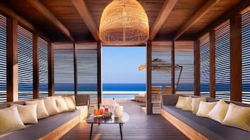 Una terraza de madera con una mesa central, dos sofás y una lámpara trenzada grande.