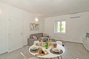 A dining area with a round table set for a meal, a sofa, and a window with natural light. - San Carlo Borromeo 1 by Wonderful Italy (Soiano del Lago)