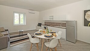 A modern kitchen with white cabinets, a stainless steel refrigerator, and a dining area with a round table and white chairs. - San Carlo Borromeo 1 by Wonderful Italy (Soiano del Lago)