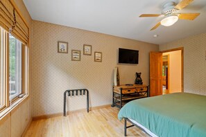 Une chambre à coucher comprenant un lit, un bureau, une chaise, un ventilateur de plafond et une fenêtre.