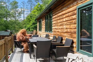Une cabane en rondins dotée d’une terrasse, de mobilier d’extérieur et offrant une vue sur la forêt environnante.
