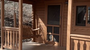 Un porche de madera con una silla y una ventana.