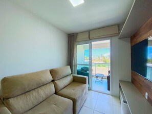 A living room with a sofa, a TV, and a sliding glass door leading to an outdoor area with a table and chairs.