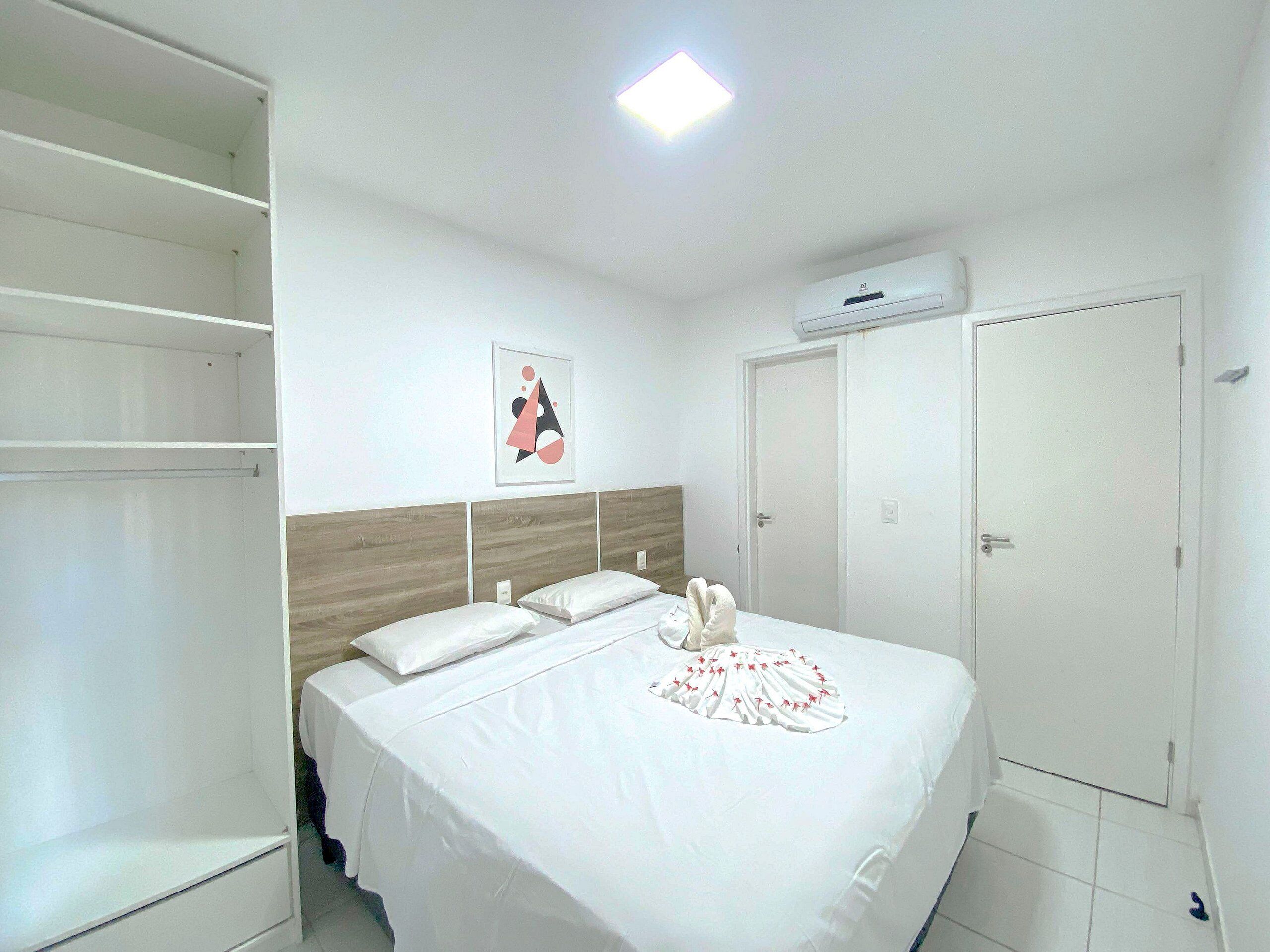 A bedroom with a bed, a wardrobe, a door, and a ceiling light.