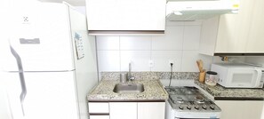 Cozinha equipada com geladeira, pia, fogão e micro-ondas.