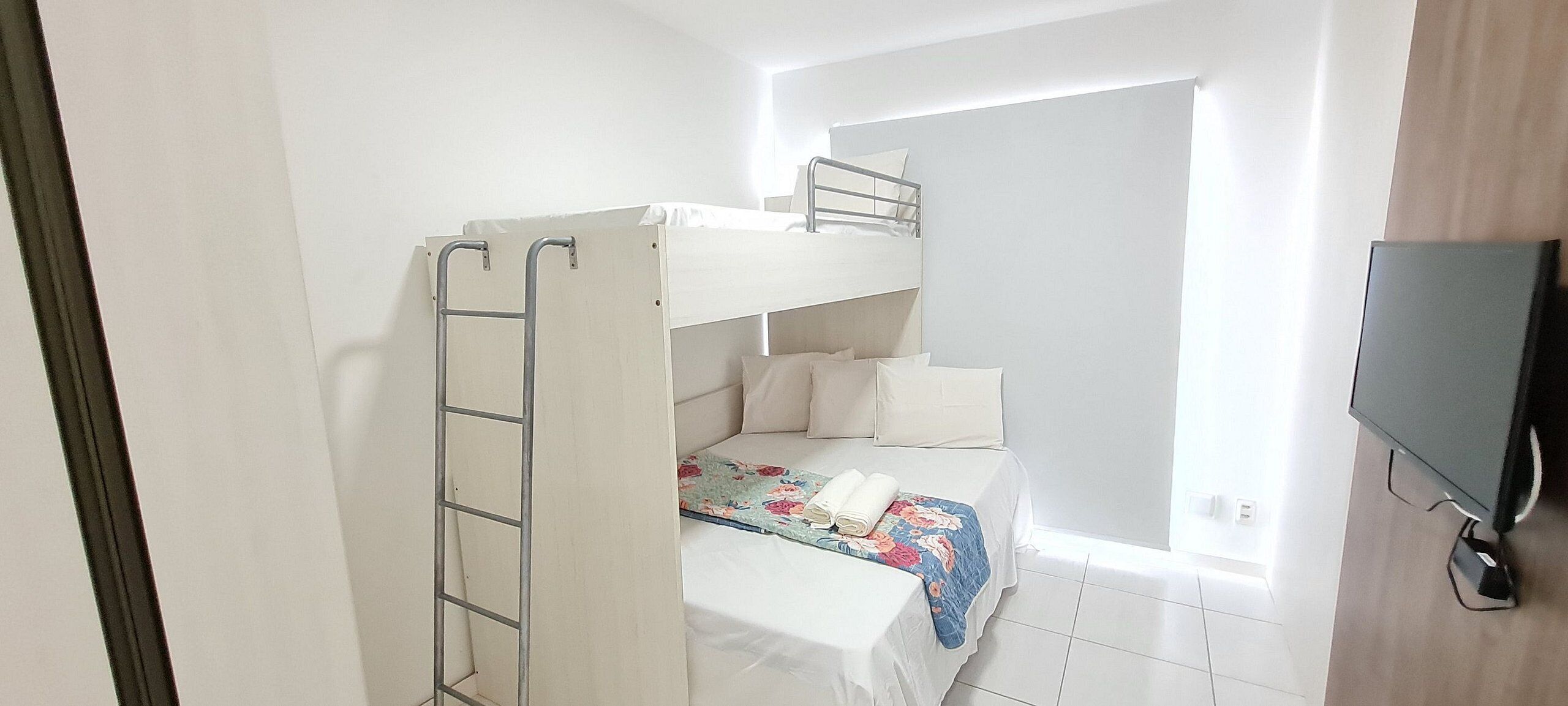 Quarto com beliche, televisão e janela.