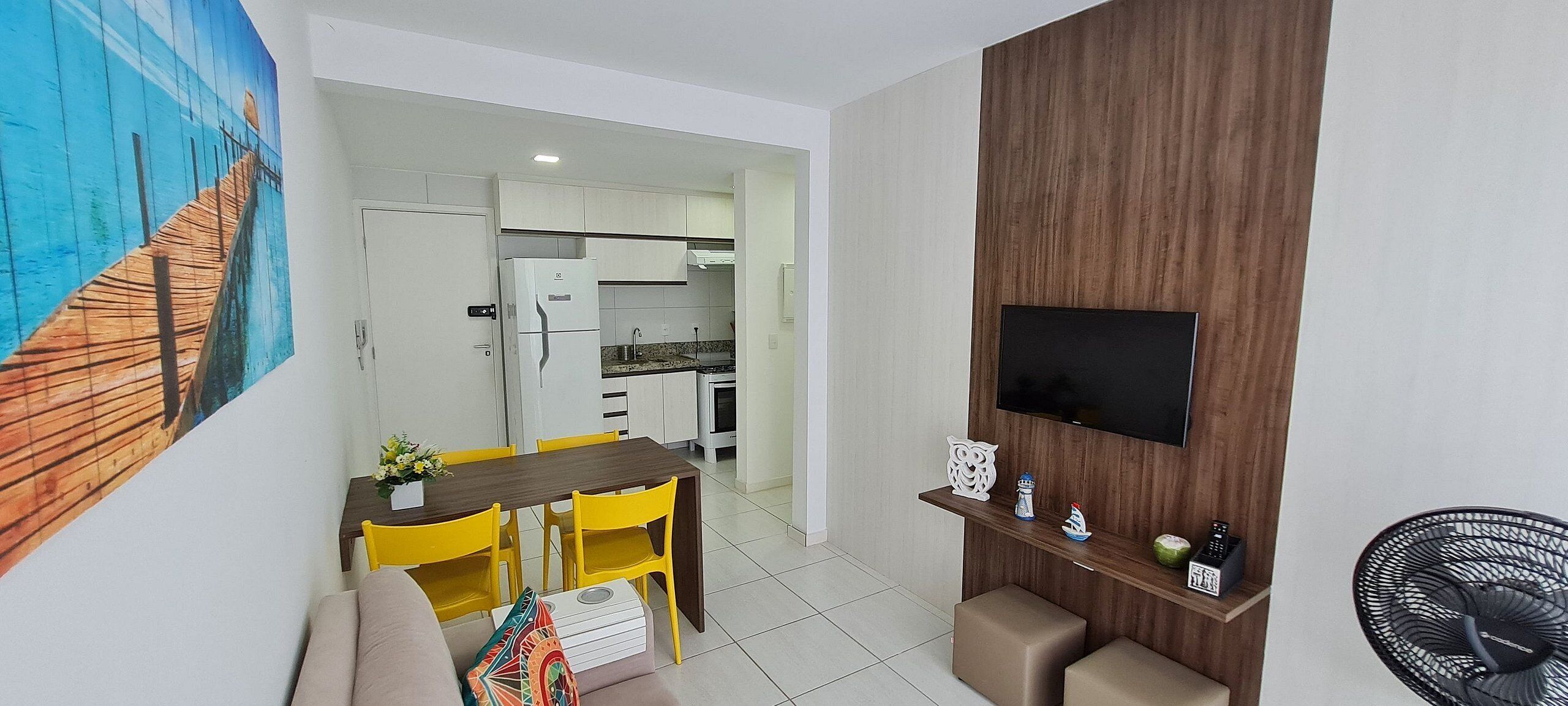A modern living space with a dining area, kitchen, and a mounted TV.