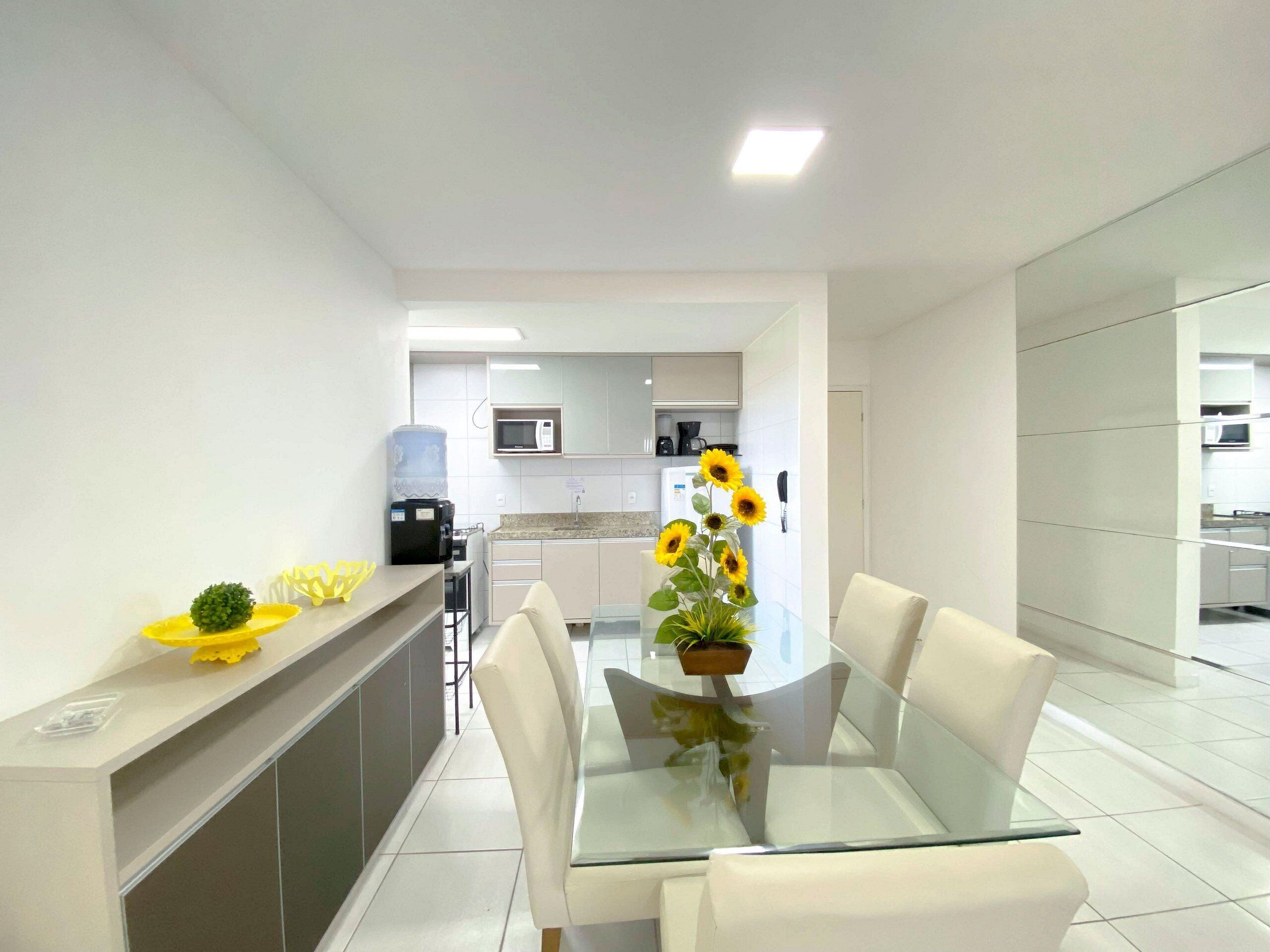 A modern kitchen with white cabinets, a microwave, and a coffee machine.