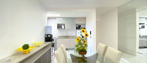 A modern kitchen with white cabinets, a microwave, and a coffee machine.