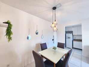 Enjoy meals in this stylish dining area with a white table and chairs, a hanging light fixture, and a wall-mounted mirror.