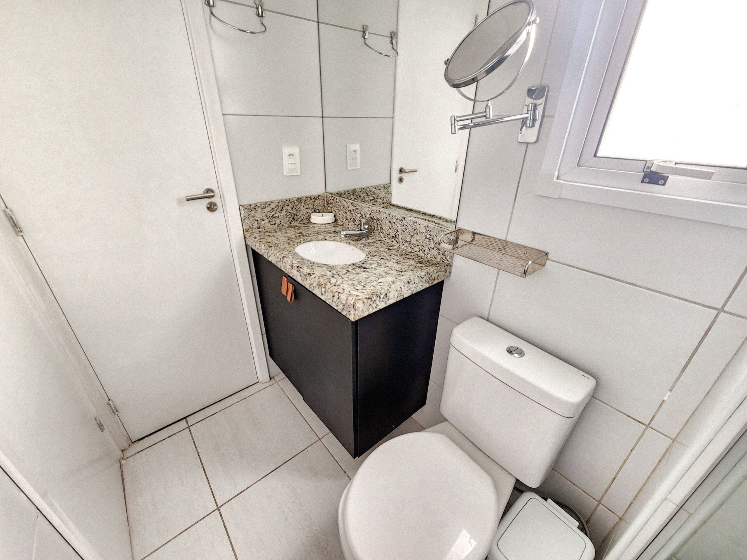 A compact bathroom with a granite countertop sink, a toilet, and a mirror.